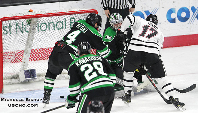 Nebraska-Omaha's Taylor Ward (17) sends the puck past North Dakota goalie Adam Scheel during the third period. Nebraska-Omaha beat North Dakota 4-3 Saturday night at Baxter Arena. (Photo by Michelle Bishop) (Michelle Bishop)